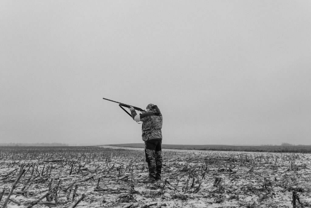 Vadászati Földtulajdonosi Közösség haszonbérleti díj kifizetés 2026. május 29. Black and white image of a hunter aiming a rifle in a desolate, snowy field.
